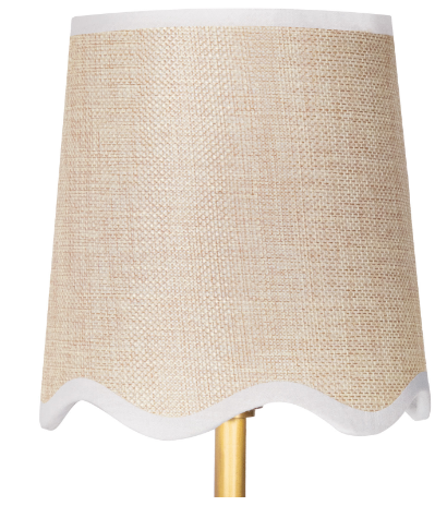 Gold wall sconce with beige shade on white wall.