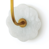 Brass and alabaster wall sconce on white wall.