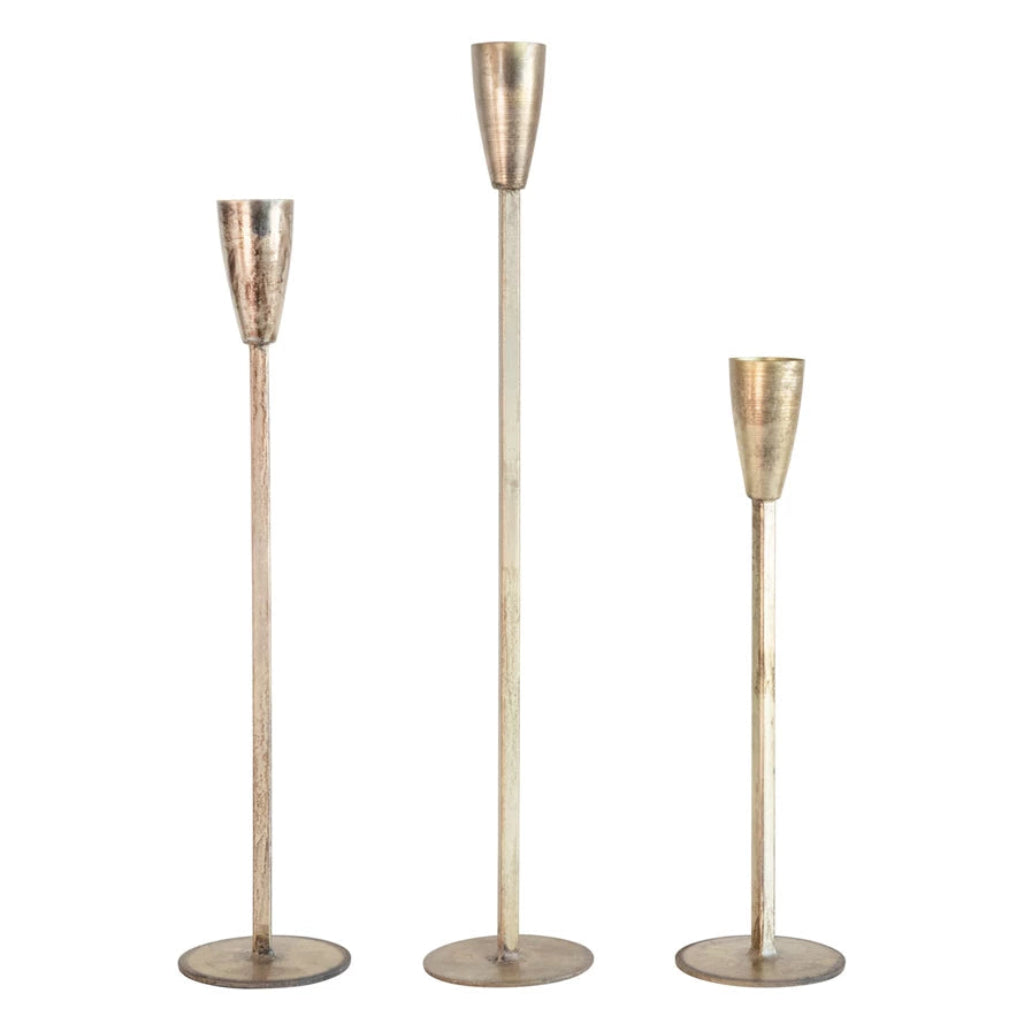 Three metallic candle holders of varying heights on a white background