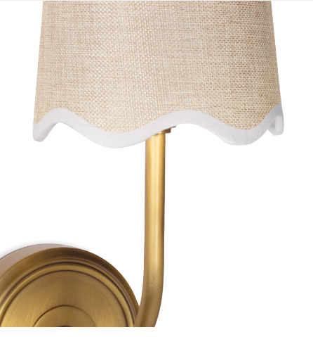 Gold wall sconce with beige lamp shade on white wall.