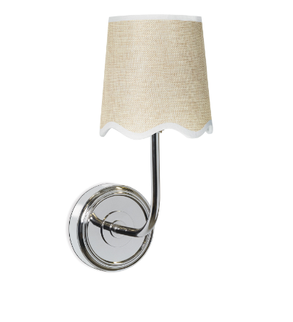 Silver wall sconce with beige shade on white wall.
