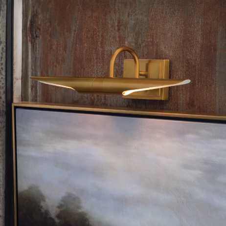 Gold redford picture light on wooden wall above artwork.