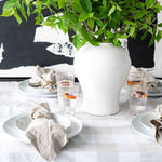 White oversized dishes on table with place settingsetting and black and white art behind