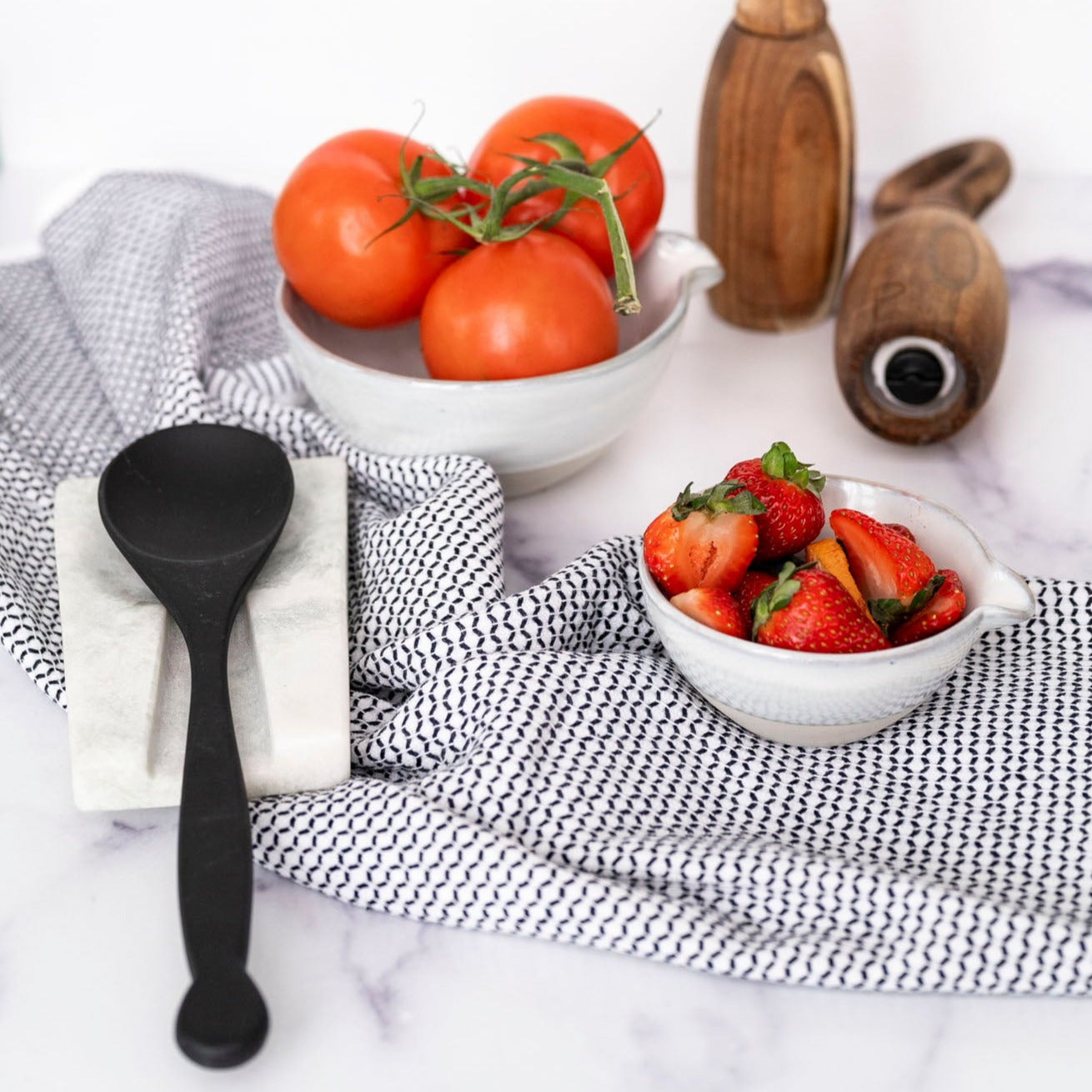 Black Dish Towel set next to bowls and spoon rest with white background