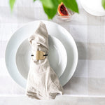 White dinner plate on table with table setting and plaid tablecloth behind