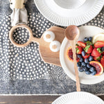 Table Runner with dot pattern on wood table with table setting and basket with black and white art behind