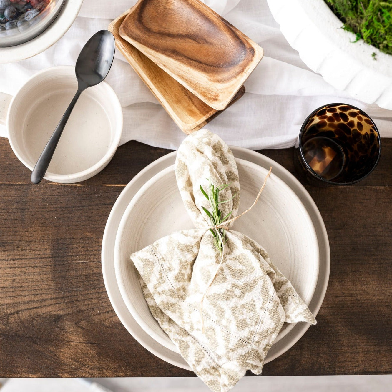 loft Reactive Glaze plate with table setting on wood table with white wall behind