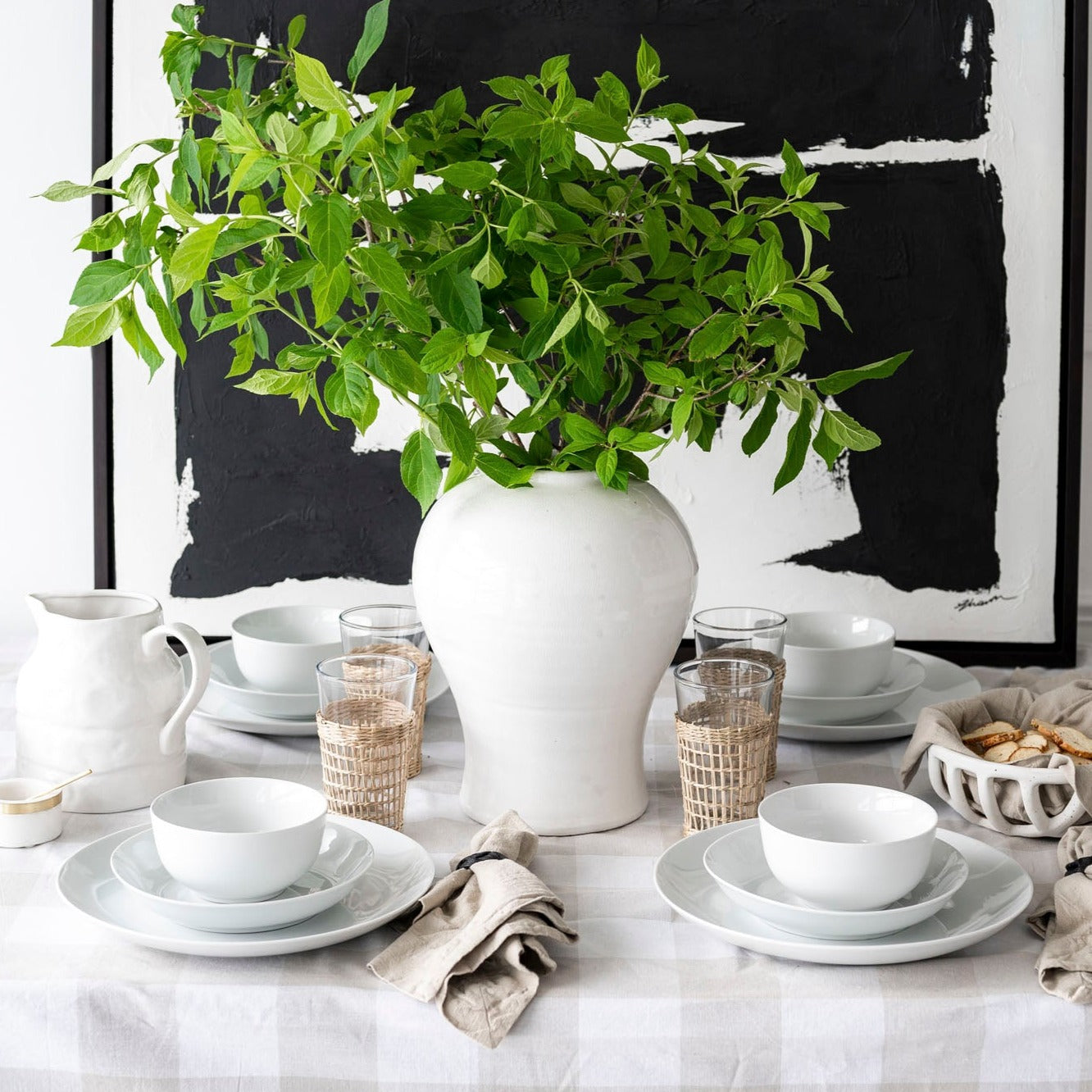 White dishes on plaid tablecloth with black and white artwork behind on white wall