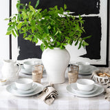 White dishes on plaid tablecloth with black and white artwork behind on white wall