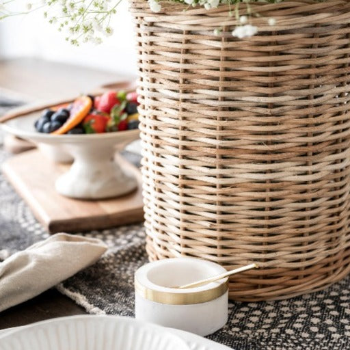 Wicker basket with flowers inside sitting on wood table