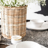 Wicker basket with flowers inside sitting on wood table