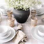 White dinnerware bowl styled with a black vase and table setting