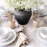 White dinnerware bowl styled with a black vase and table setting