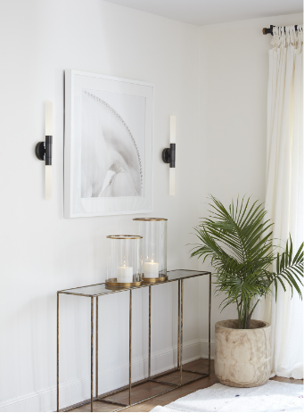 Silver sconce on white wall with artwork and entryway table.