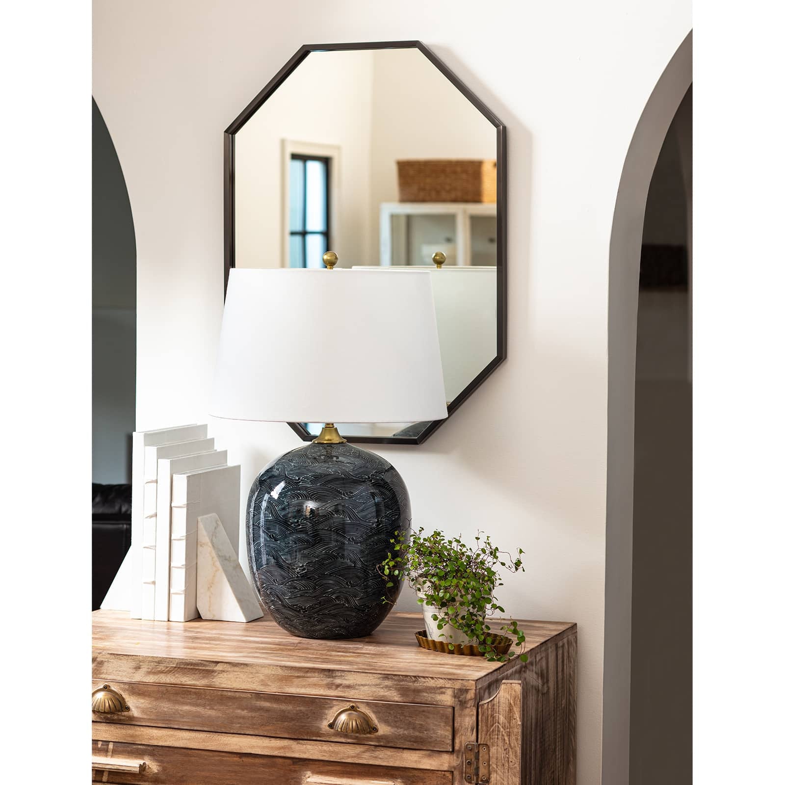 Harbor ceramic lamp on wood table in front of black mirror on white wall.