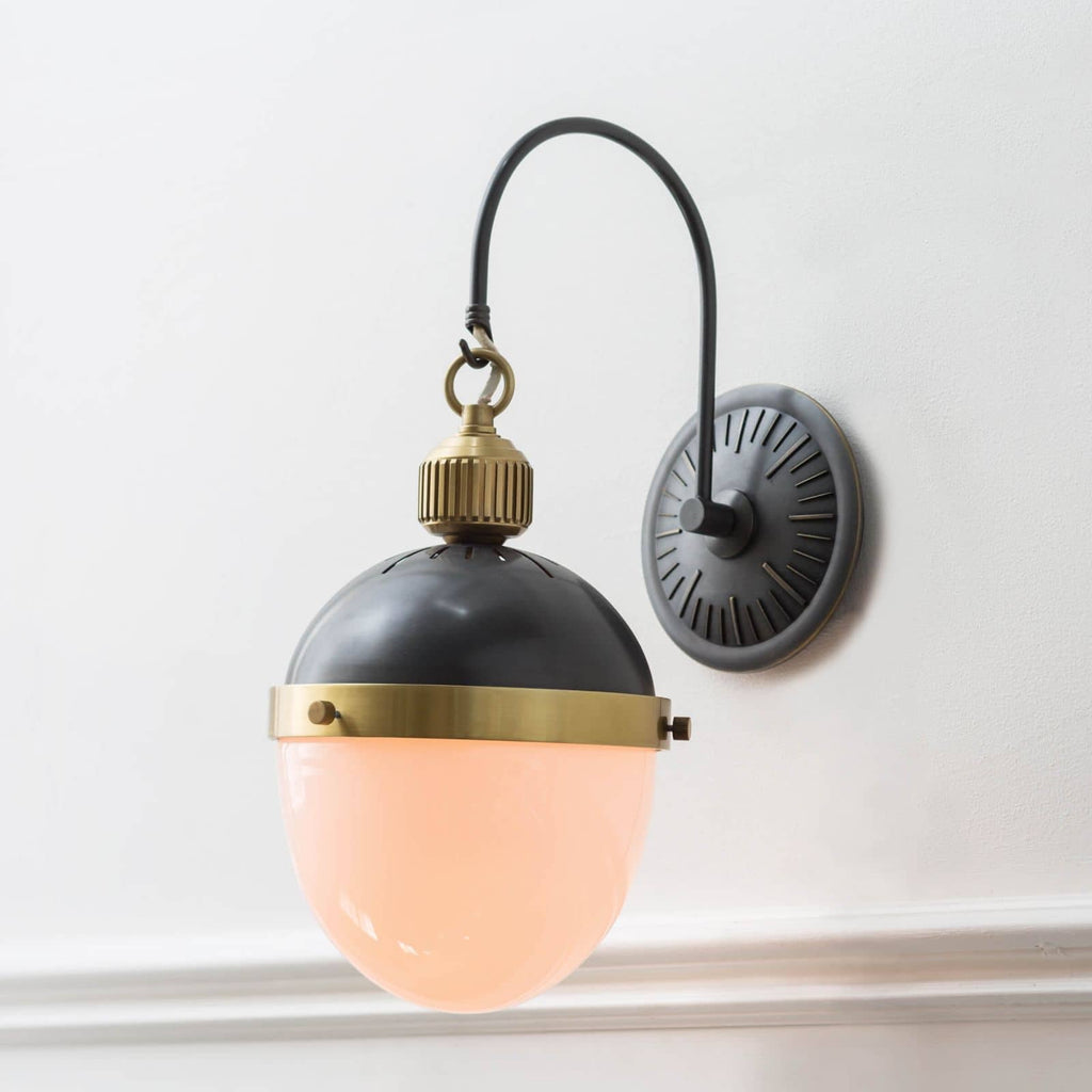 Black and gold otis sconce on white wall.